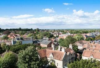 Arial image of a village with country houses and lots of trees with bright blue sky