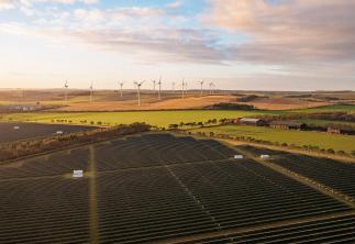 Solar panels and wind turbines in fields with the sunset in sky