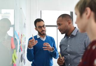 Team members talking with a white board in front of them