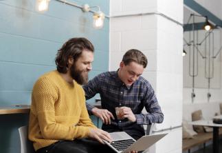 Two gentlemen working on a laptop together