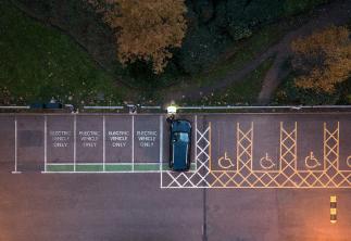 Ariel image of car park and person putting their EV car on charge