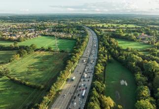 Contrast of motorway in the middle of image and green fields both sides