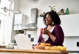 Lady sat at laptop smiling with a cup of tea