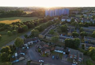 Landscape showing green field and trees with houses and tower flats-GettyImages-1407388421