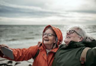 two ladies at the beach in the wind taking a selfie