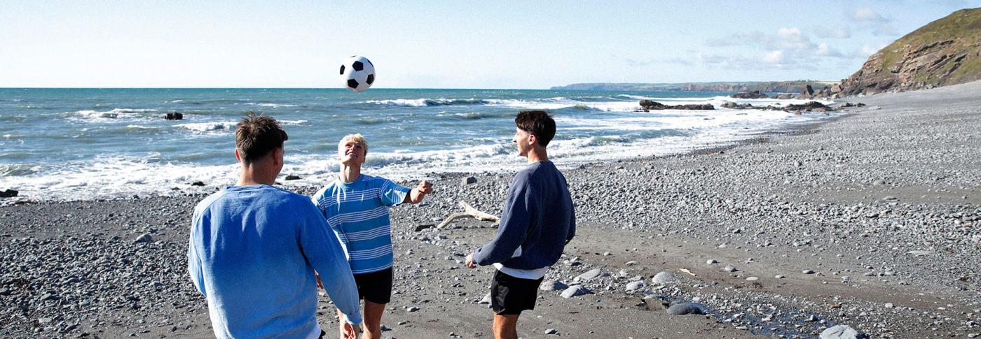 Group of men playing football on the beach