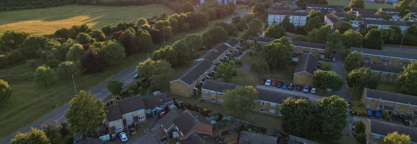 Landscape showing green field and trees with houses and tower flats-GettyImages-1407388421