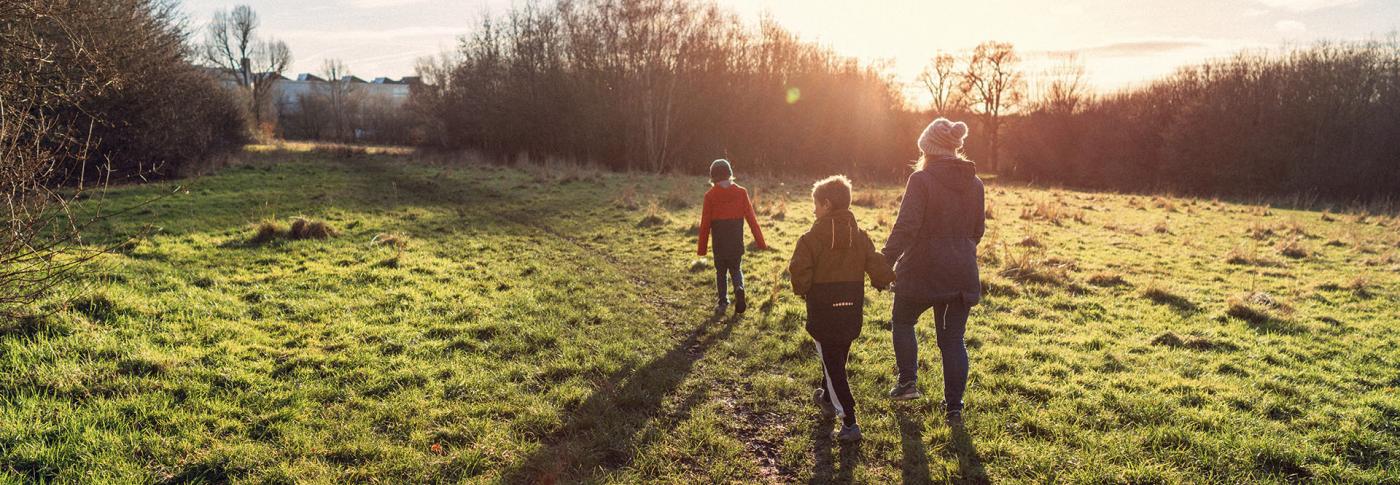 family walking through field in sunset