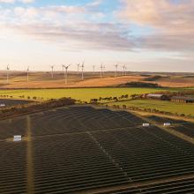 Solar panels and wind turbines in fields with the sunset in sky