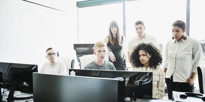 Group of people sat around computer talking