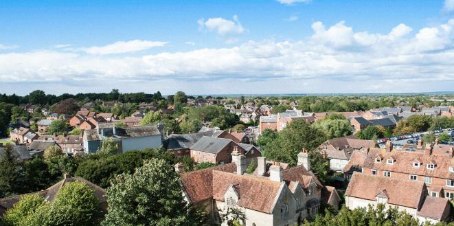 Arial image of a village with country houses and lots of trees with bright blue sky