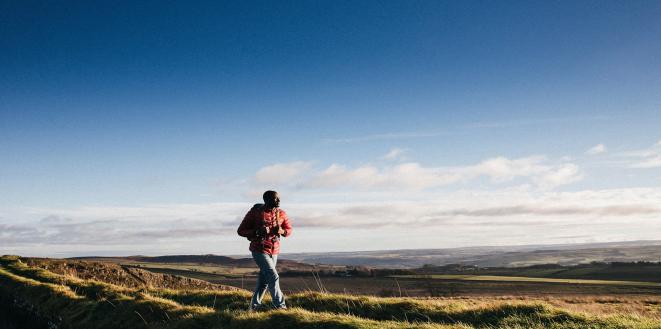 Person walking on top of hill with bright blue skies