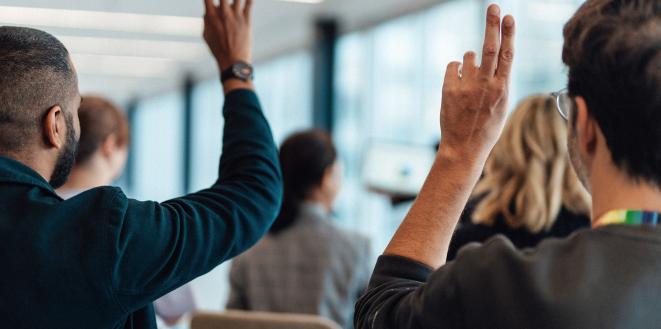 People in meeting with their hands up