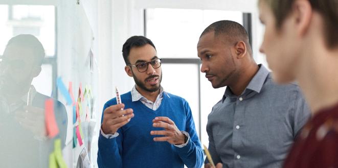 Team members talking with a white board in front of them