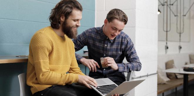 Two gentlemen working on a laptop together