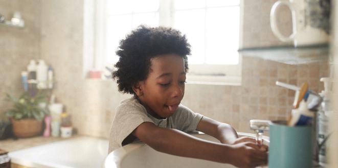 Child washing their hands in the bathroom