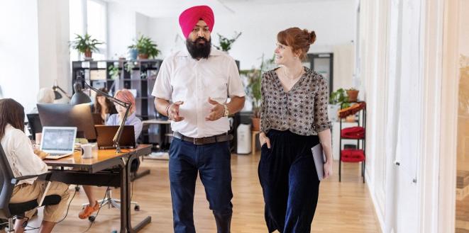 Colleagues walking together having a chat in office environment