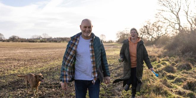 Happy couple on dog walk in field