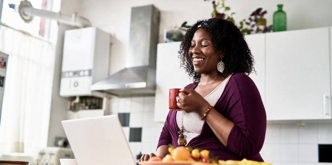 Lady sat at laptop smiling with a cup of tea