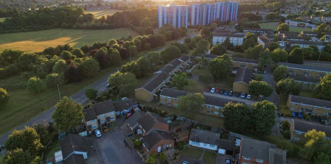 Landscape showing green field and trees with houses and tower flats-GettyImages-1407388421