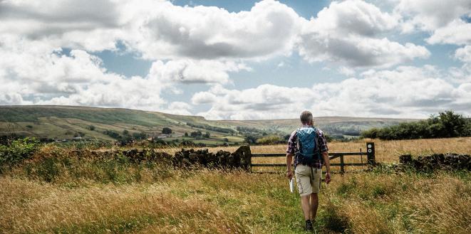 Man walking on country path through field