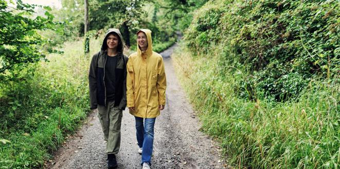 Two people walking through woods in the rain