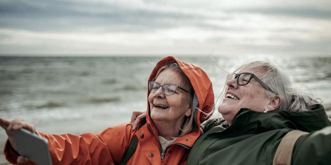 two ladies at the beach in the wind taking a selfie