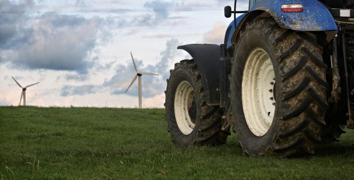 Big blue tractor and wind turbines in background