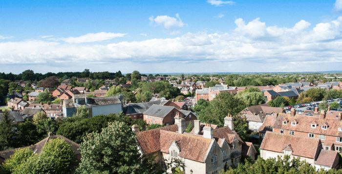 Arial image of a village with country houses and lots of trees with bright blue sky