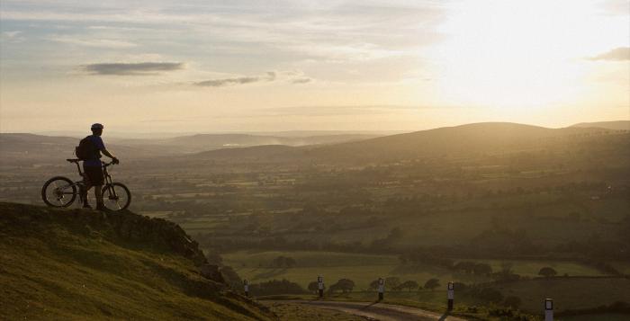 Person on mountain bike up mountain watching the sunrise