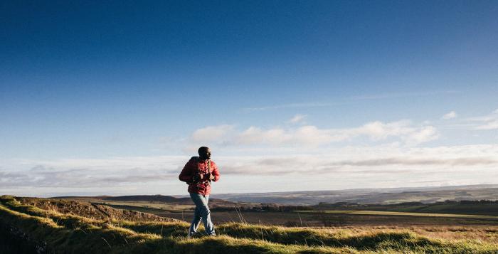 Person walking on top of hill with bright blue skies