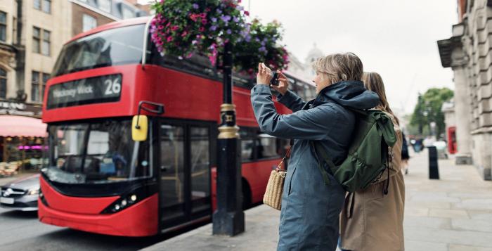 Tourists taking photos of London bus-GettyImages-1642377261