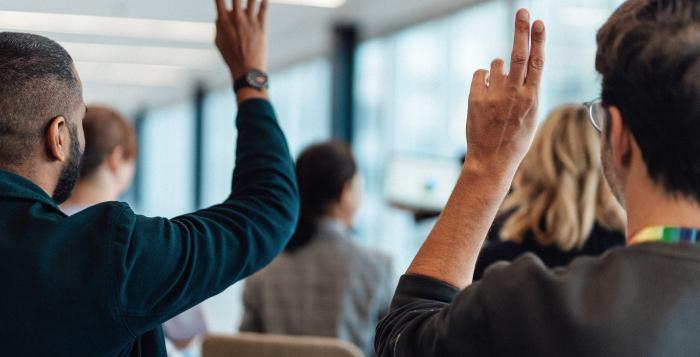 People in meeting with their hands up