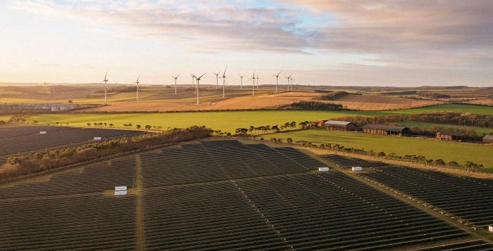 Solar panels and wind turbines in fields with the sunset in sky