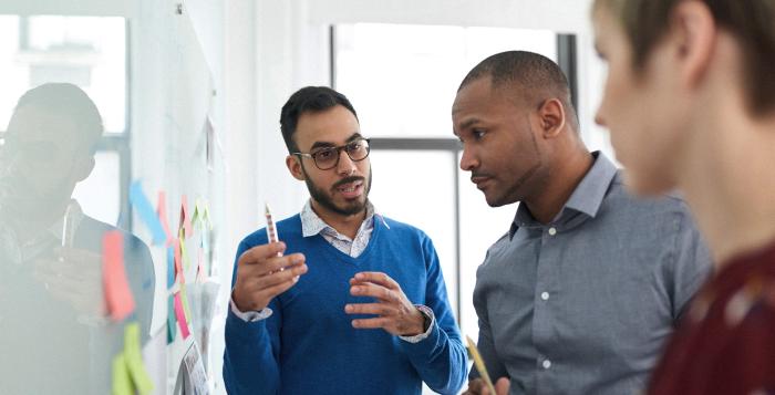 Team members talking with a white board in front of them