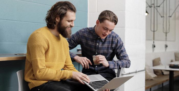 Two gentlemen working on a laptop together