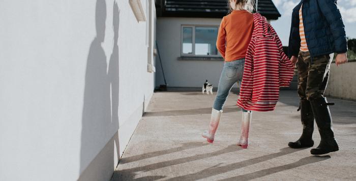 Children walking towards a cat to give it a pe