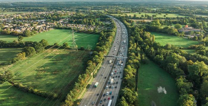 Contrast of motorway in the middle of image and green fields both sides