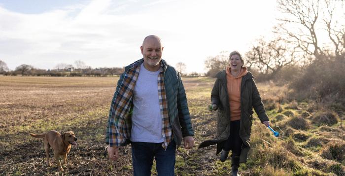 Happy couple on dog walk in field