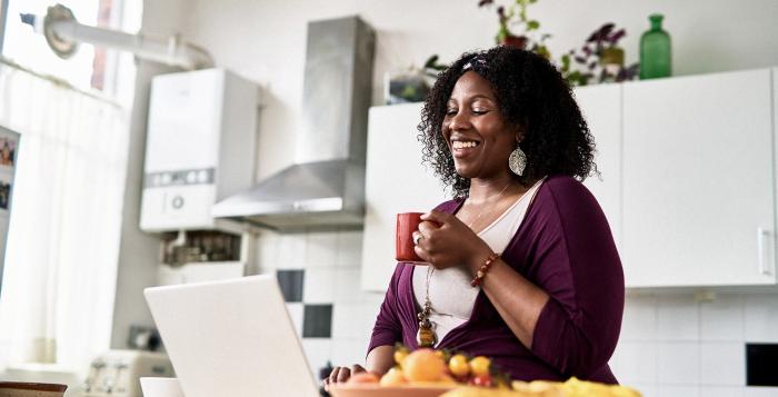 Lady sat at laptop smiling with a cup of tea