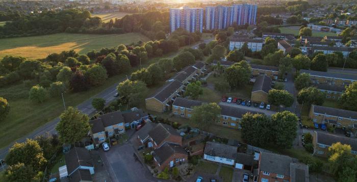 Landscape showing green field and trees with houses and tower flats-GettyImages-1407388421