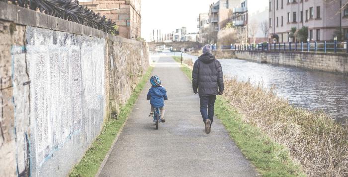 Man walking with child riding bike