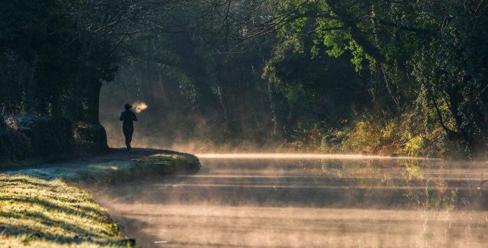 Person running alongside canal with evaporation steam