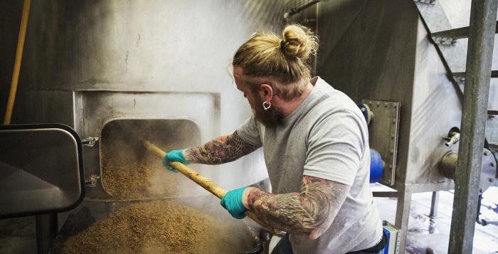 Person with man bun and tattoos working in a brewery