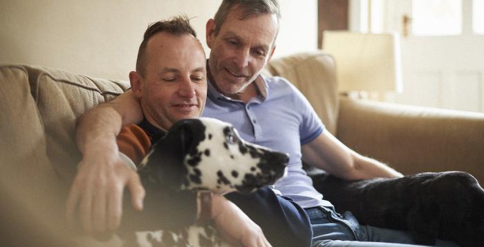 Two men sat on sofa with their Dalmatian dog