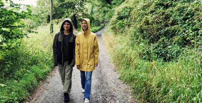 Two people walking through woods in the rain