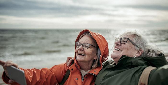 two ladies at the beach in the wind taking a selfie